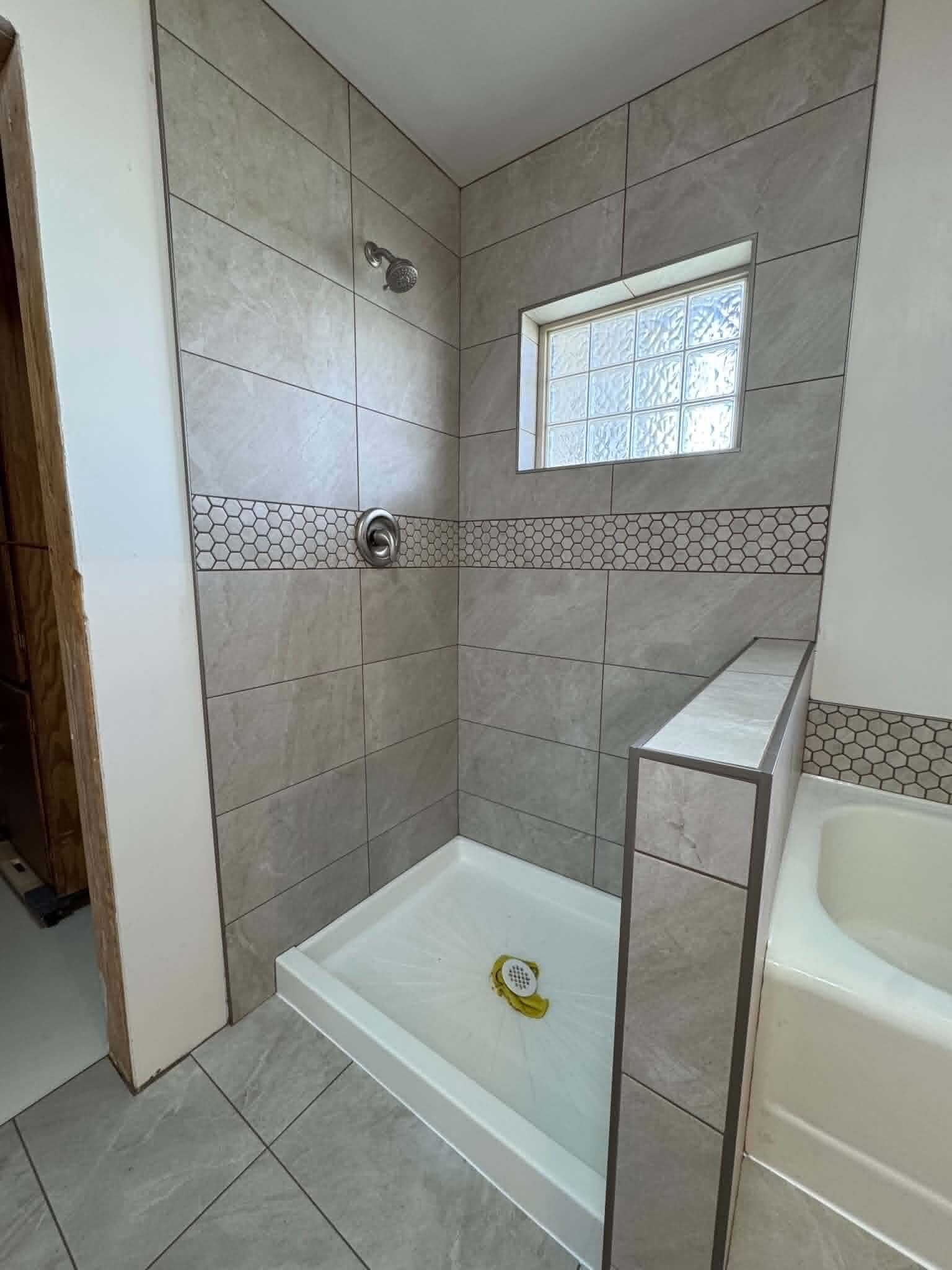 Bathroom tile wall with accent band installed by MG Flooring
