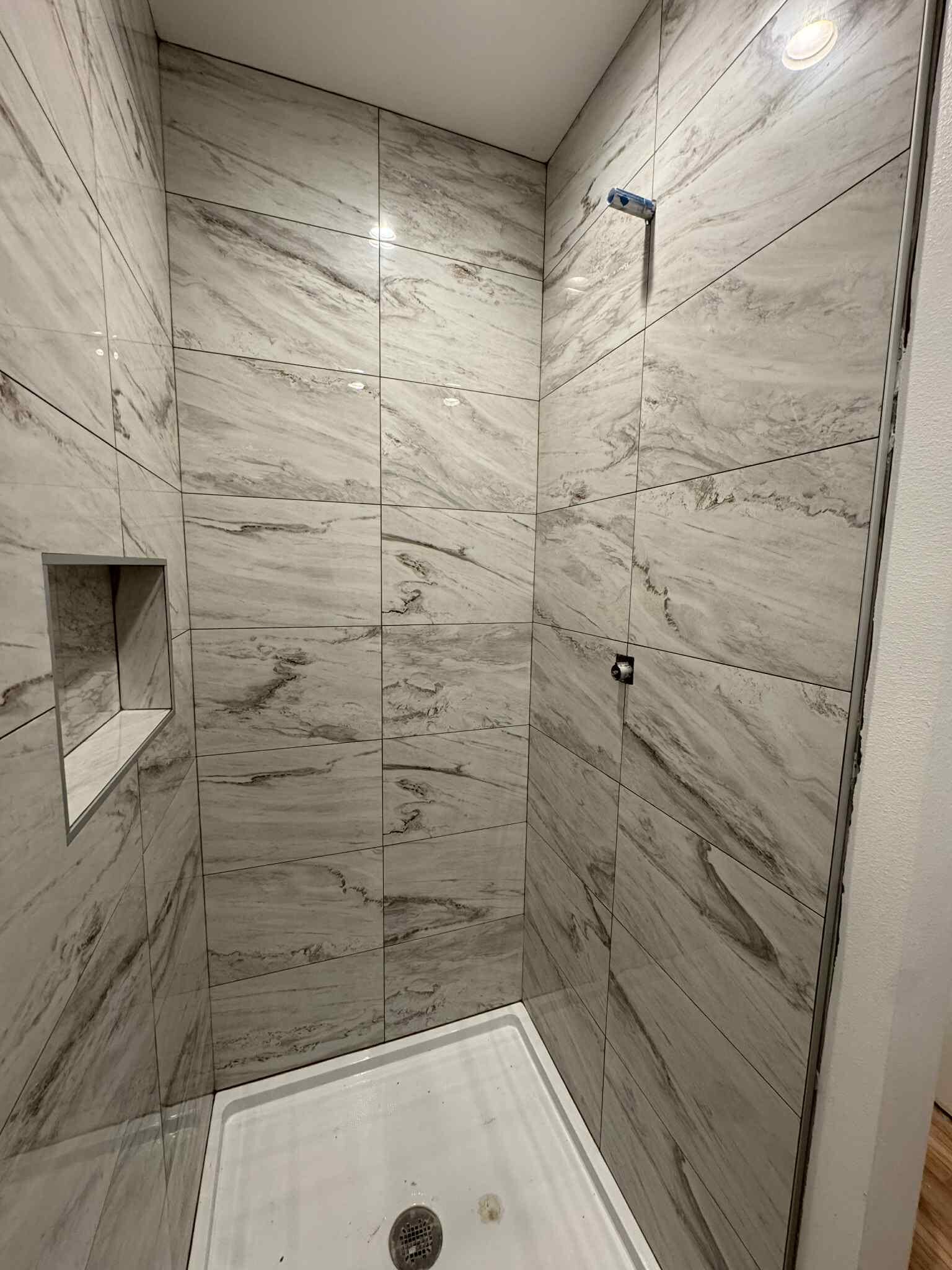 Marble-look tile shower with built-in niche installed by MG Flooring